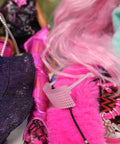 Close-up of a doll with pink hair and colorful outfit, surrounded by other dolls.