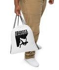 White Gravity Is a Myth drawstring bag carried by a person wearing beige trousers, showing the single black climber design on the front.