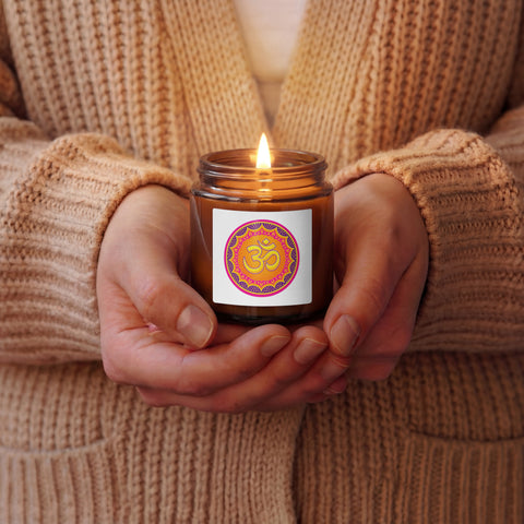Vibrant Om Mandala Christmas Warmth 4 oz soy candle in an amber glass jar, held by a person wearing a beige knitted cardigan, with one complete colourful mandala front label.