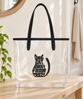 One Cat Away from Crazy clear tote bag with black handles and one complete black cat-shaped front print, standing on a pale wooden bench in a bright home entryway beside a green plant.