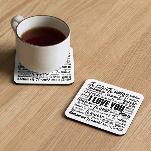 Love in Every Language coaster on a wooden table beside a cup resting on a matching printed coaster.