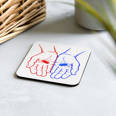 Red or Blue Choice glossy coaster on a pale stone tabletop beside a wicker basket and plant, showing the complete red and blue hands artwork on its white front.