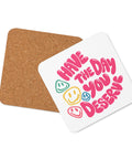 Glossy white cork-back coaster with original pink Have the Day You Deserve lettering and colourful smiley faces centred in full – ZIPZAPPA