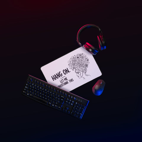 White Overthink This desk mat on a gaming desk beside a mouse and headphones.