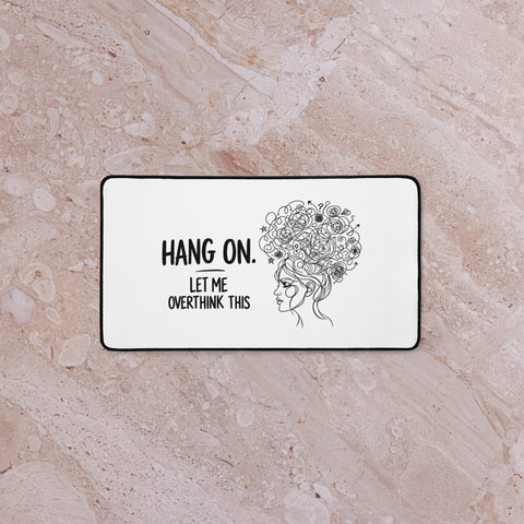 Medium white Overthink This desk mat on a pale marble surface, viewed from above.