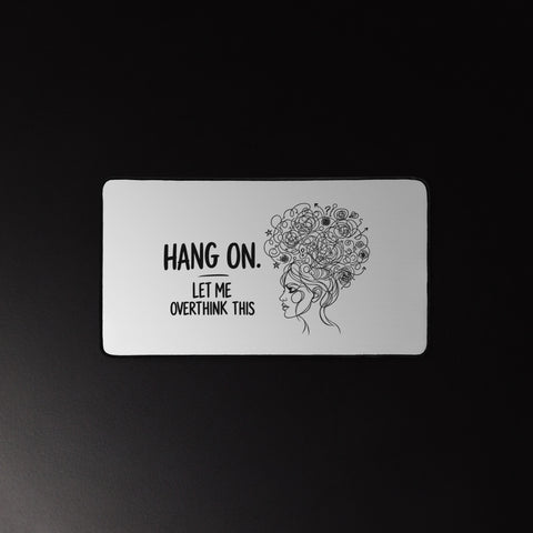 Medium white Overthink This desk mat beneath a mouse and keyboard on a dark desk.