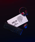 Medium white Overthink This desk mat on a gaming desk beside a mouse and headphones.