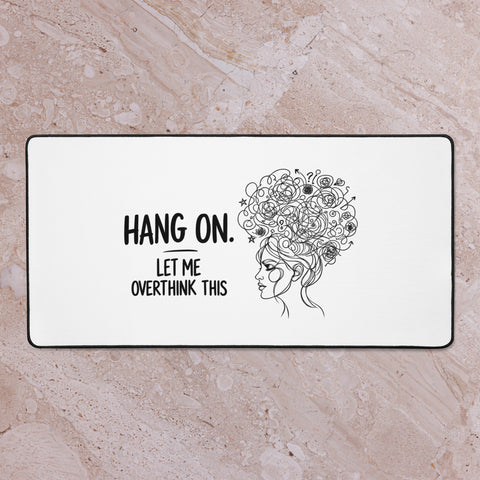 Large white Overthink This desk mat on a pale marble surface, viewed from above.