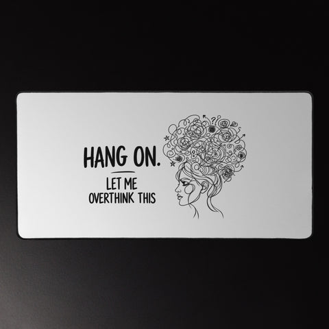 Large white Overthink This desk mat beneath a mouse and keyboard on a dark desk.