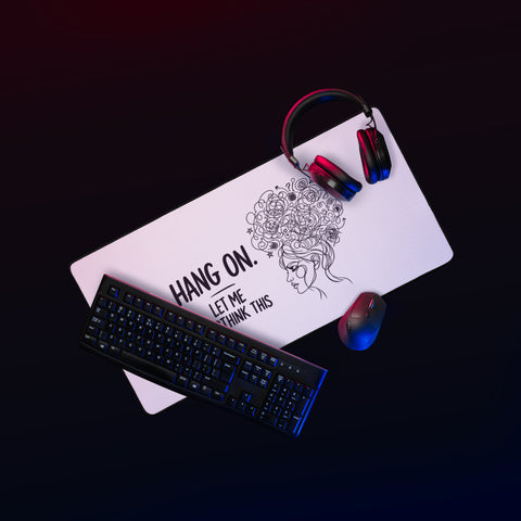 Large white Overthink This desk mat on a gaming desk beside a mouse and headphones.
