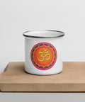 White 12 oz enamel mug with a silver rim and a pink, purple and golden-orange Om mandala on the front, shown on a wooden board; front view.