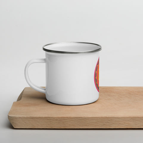 White 12 oz enamel mug with a silver rim and a pink, purple and golden-orange Om mandala on the front, shown on a wooden board; left-side view.