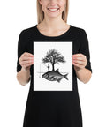 Model holding the Angler’s Island black-and-white matte poster featuring a fisherman, tree and giant fish