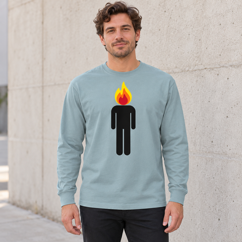 Male model wearing an Agave heavyweight long-sleeve tee with a black human figure and yellow, orange and red flame head, standing by a pale concrete wall.