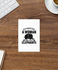 Elephant Lover 4 × 6 inch greeting card on a wooden desk beside coffee, a keyboard and a notebook, showing one black elephant design on the front.