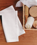 Golden Loop white hand towel with gold-tone geometric emblem on black square – lifestyle view