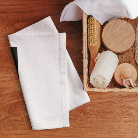 Golden Loop white hand towel with gold-tone geometric emblem on black square – lifestyle view