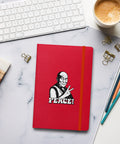 Red Peace Sign Monk hardcover lined notebook on a desk beside coffee, a white keyboard and pencils, showing one complete black-and-white monk and PEACE! front design.