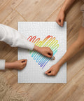 Rainbow Heart 520-piece jigsaw puzzle with one complete colourful heart and surrounding white space, being assembled by two people on a wooden table.