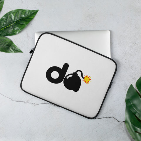 13-inch white D-Bomb Spark laptop sleeve with black trim and black D and cartoon bomb artwork with a yellow-red spark, shown with a laptop and green leaves.