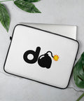 15-inch white D-Bomb Spark laptop sleeve with black trim and black D and cartoon bomb artwork with a yellow-red spark, shown with a laptop and green leaves.