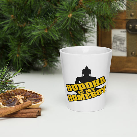 Printed front of a white Buddha Is My Homeboy latte mug beside pastries and green branches.