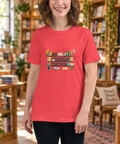 Model wearing the Heather Red No Shelf Control women’s relaxed tee in a sunlit bookstore with wooden shelves and plants, showing one complete book-themed front print.