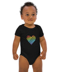 Baby modelling the black Rainbow Heart organic cotton bodysuit, viewed from the front.