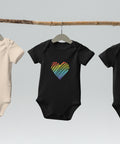 The black Rainbow Heart organic cotton baby bodysuit hanging on a clothes rail.