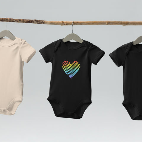 The black Rainbow Heart organic cotton baby bodysuit hanging on a clothes rail.