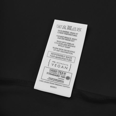 Fabric label detail on the black Rainbow Heart organic cotton bodysuit.