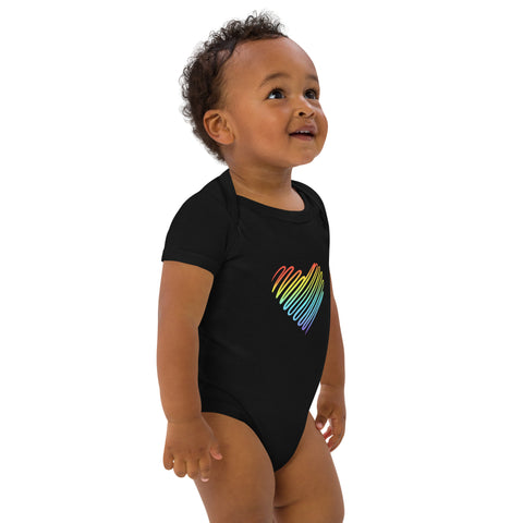 Side view of a baby wearing the black Rainbow Heart organic cotton bodysuit.