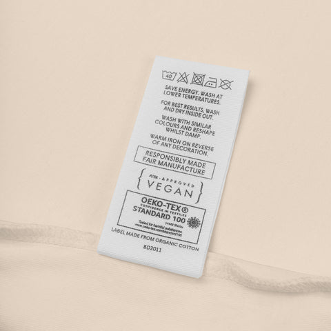 Fabric label detail on the organic natural Rainbow Heart organic cotton bodysuit.