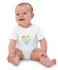 Seated baby wearing the white Rainbow Heart organic cotton bodysuit.