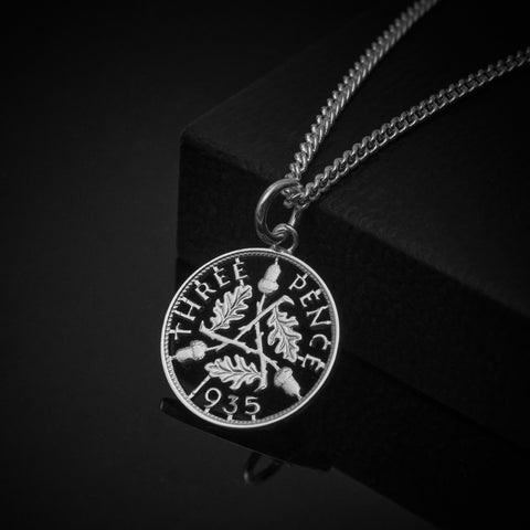 Silver coin pendant on a chain against a black background