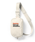 Ivory sling bag with full orange and black Karma Has No Deadline lettering high on the front