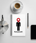 Find Yourself spiral notebook with a red location-pin figure on a desk beside coffee, a pencil, a moka pot, and a phone.