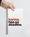 White spiral notebook with rust-orange and black Karma Has No Deadline lettering centred on the front cover – ZIPZAPPA