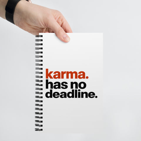 White spiral notebook with rust-orange and black Karma Has No Deadline lettering centred on the front cover – ZIPZAPPA