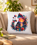 White Sunset Cat decorative pillow on a beige sofa in a sunlit living room beside a book and green plants.