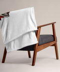 Fire Wolf throw blanket draped over a wooden armchair showing its plain white reverse side.