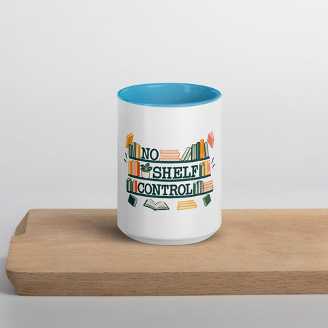 15 oz white No Shelf Control ceramic mug with blue interior, rim and handle, front view on a wooden board; book illustration and green lettering printed once on the front.