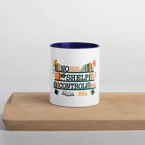11 oz white No Shelf Control ceramic mug with dark blue interior, rim and handle, front view on a wooden board; book illustration and green lettering printed once on the front.