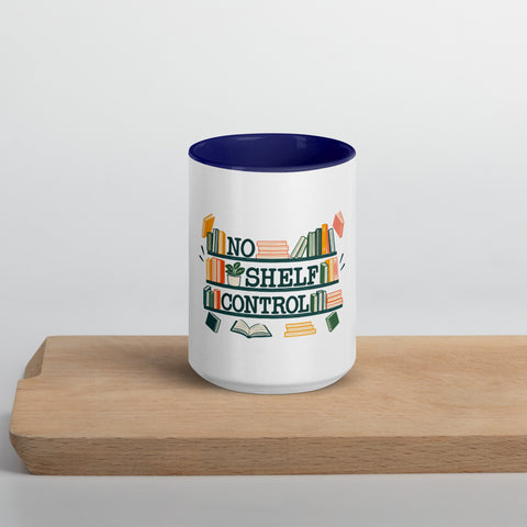 15 oz white No Shelf Control ceramic mug with dark blue interior, rim and handle, front view on a wooden board; book illustration and green lettering printed once on the front.
