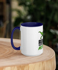 Left-side view of the 15 oz Dinosaur Motivation ceramic mug with dark blue interior and handle on a round wooden table with softly blurred greenery, showing its single front design.