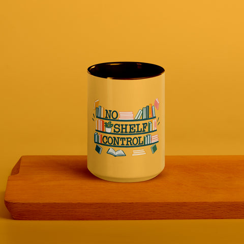 15 oz white No Shelf Control ceramic mug with golden yellow interior, rim and handle, front view on a wooden board; book illustration and green lettering printed once on the front.