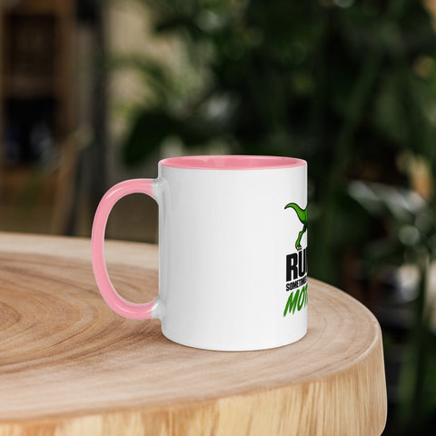 Left-side view of the 11 oz Dinosaur Motivation ceramic mug with pink interior and handle on a round wooden table with softly blurred greenery, showing its single front design.