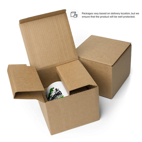 Packaging example: The 15 oz Dinosaur Motivation ceramic mug with red interior and handle in an open cardboard shipping box. Actual packaging may vary by delivery location.