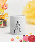 Cross-Bearing Warrior 11 oz glossy white ceramic mug with one complete black-and-white warrior and cross front print, beside yellow flowers and colourful fruit.