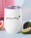White Travel More, Worry Less insulated wine tumbler with a lid and one black front design, standing beside grapefruit and limes.